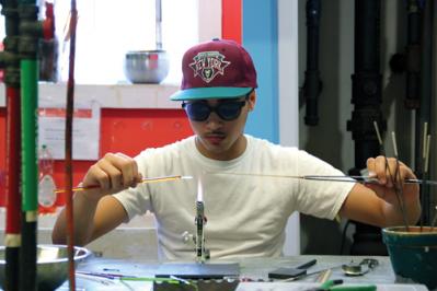 Bird Street Glass-blowers: Dany Melo, 15, makes glass beads as part of a glass-blowing program for boys through the Bird Street Community Center. Photo by Elizabeth Murray